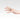 Hand wearing a ring with a pink gemstone on a plain background